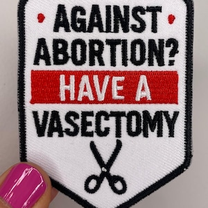 Op de afbeelding: Een witte patch met zwarte tekst die luidt: "AGAINST ABORTION? HAVE A VASECTOMY." De tekst staat in een zwarte rand met een rode streep. Onderaan staat een schaar.