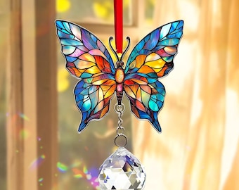 May include: A stained-glass butterfly suncatcher with a faceted crystal ball. The butterfly features a colorful mosaic design with blue, orange, yellow, and purple hues. It hangs from a red ribbon, creating a decorative accent.