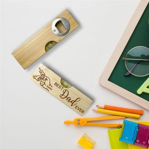 Op de afbeelding: Twee houten waterpas flesopeners, &eacute;&eacute;n met een flesopener en de andere met de tekst "Best Dad Ever". De openers zijn lichtbruin met een zilveren flesopener en een waterpas.