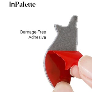 May include: A silver adhesive sticker with a red backing is being peeled away. The sticker has a unique shape and is designed for damage-free application. The text "Damage-Free Adhesive" is visible. The brand name "InPalette" is also visible.