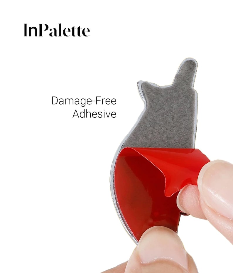 May include: A silver adhesive sticker with a red backing is being peeled away. The sticker has a unique shape and is designed for damage-free application. The text "Damage-Free Adhesive" is visible. The brand name "InPalette" is also visible.