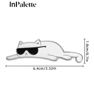 May include: A white cat-shaped pin with black sunglasses, measuring 6.4cm long and 1.8cm high. The pin has a silver outline and is in a relaxed pose. The text "InPalette" is at the top.