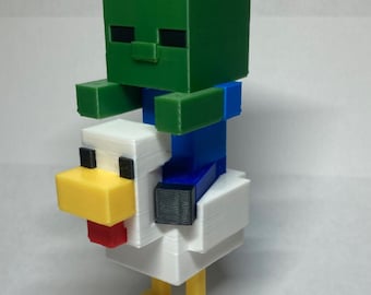 Könnte beinhalten: Eine grüne Minecraft-Zombiefigur, die auf einer weißen Hühnerfigur mit gelben Beinen reitet. Die Zombiefigur hat blaue Arme und Beine.