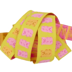 May include: Yellow ribbon with a repeating pattern of pink and orange gummy bears. The ribbon is curled and layered, with a pink and orange striped pattern visible on the edges.