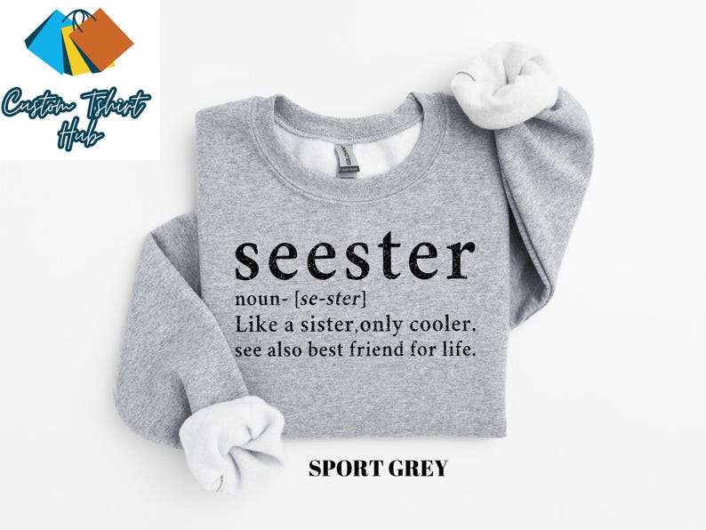 May include: A gray sweatshirt with the text "seester" defined as "Like a sister, only cooler. See also best friend for life." in black text. The sweatshirt is labeled "SPORT GREY".