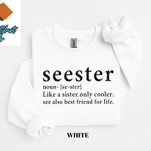 May include: White t-shirt with black text that reads "seester" defined as "noun- [se-ster] Like a sister, only cooler. see also best friend for life."