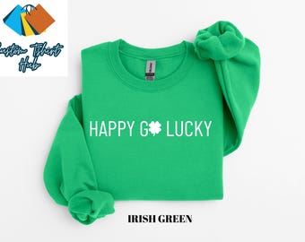 May include: A bright green sweatshirt with the words "HAPPY G🍀LUCKY" in white, with a shamrock graphic. The text "IRISH GREEN" is below the sweatshirt. The sweatshirt is a crew neck style.