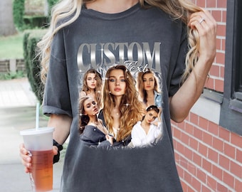 May include: A gray t-shirt with a silver graphic of the word "CUSTOM" with the word "Text" underneath. The graphic is surrounded by images of women with long hair.