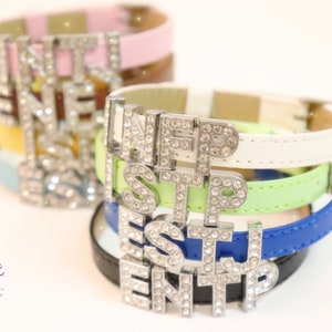 May include: Stack of colorful leather bracelets with a silver charm spelling out "INFP ESTJ ENTP".