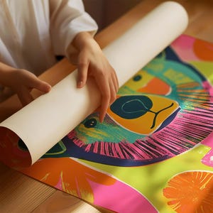 Op de afbeelding: Een kleurrijke poster met een gestileerde illustratie van een berenkop in felle gele, groene, roze en blauwe kleuren. De poster is opgerold en wordt vastgehouden door iemands handen.