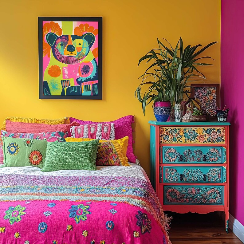Op de afbeelding: Een kleurrijke slaapkamer met een felgele muur, een bed met een roze en veelkleurige bedsprei en een dressoir met bloemmotieven. Het dressoir heeft drie lades en is geschilderd in tinten blauw, groen en oranje. Er hangt een ingelijst afdruk van een kleurrijke beer aan de muur boven het bed.