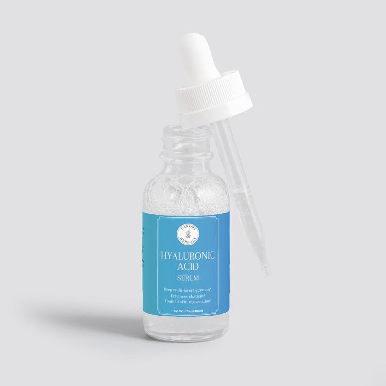 Puede incluir: Una botella de vidrio transparente con una etiqueta azul y blanca que dice "HYALURONIC ACID SERUM". La botella tiene un tap&oacute;n cuentagotas blanco y est&aacute; llena de un l&iacute;quido transparente.