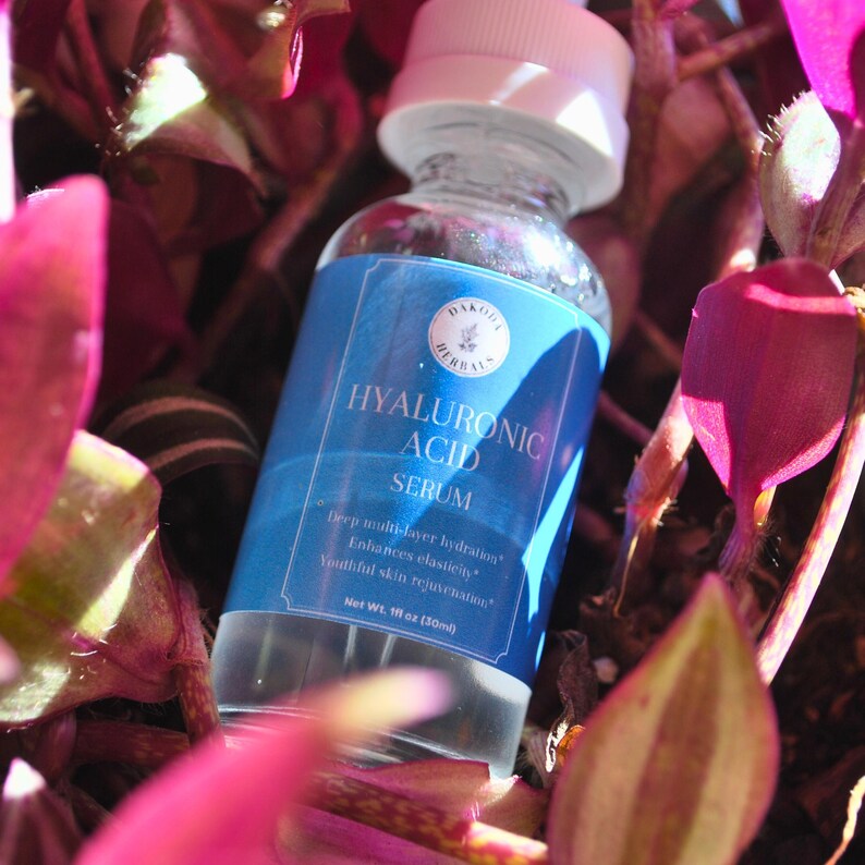 Puede incluir: Una botella de vidrio azul con tapa blanca que contiene suero de &aacute;cido hialur&oacute;nico. La botella est&aacute; etiquetada con el texto "DAKO HERBALS" y "HYALURONIC ACID SERUM". La etiqueta tambi&eacute;n incluye el texto "Hidrataci&oacute;n multicapa profunda", "Mejora la elasticidad", "Rejuvenecimiento de la piel", y "Peso neto 1 fl oz (30ml)".