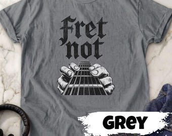 May include: A grey t-shirt with the words "Fret not" in a gothic font above a black and white illustration of hands playing a guitar. The word "GREY" is written in a white font on a grey background.