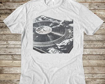 May include: A black and white photo of a hand mixing a record on a turntable. The turntable is a classic style with a black vinyl record on it.