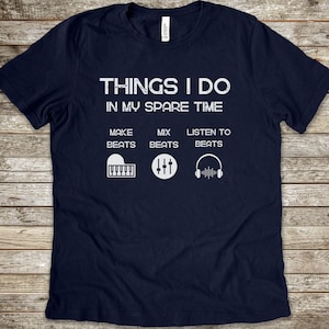 May include: A navy blue short-sleeve t-shirt featuring white text that reads THINGS I DO IN MY SPARE TIME, followed by three columns: MAKE BEATS with a piano icon, MIX BEATS with a sound mixer icon, and LISTEN TO BEATS with a headphone icon.