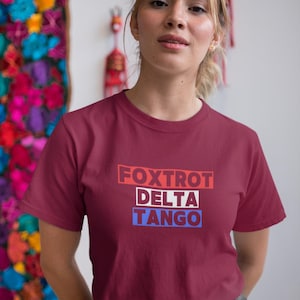 May include: A maroon t-shirt with the words "FOXTROT DELTA TANGO" printed in red, white, and blue.
