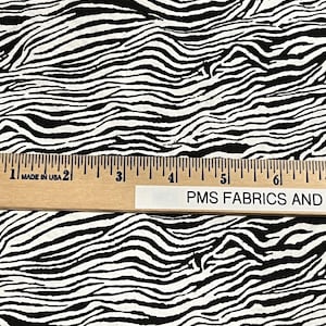 May include: Black and white zebra print fabric. The fabric is shown with a ruler measuring 6 inches.