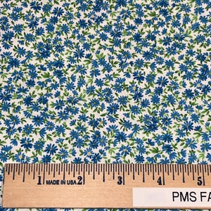 May include: White fabric with a blue and green floral pattern. The fabric is measured with a ruler that reads "Made in USA".