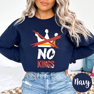 May include: Navy blue sweatshirt with a graphic that says "NO KINGS" in white and red text, with a crossed-out crown design. The sweatshirt is a solid navy color, and the text is centered on the chest.