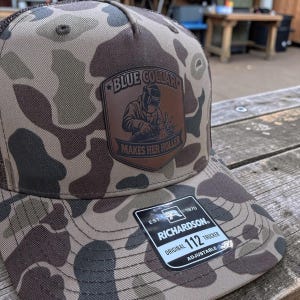 May include: A white ceramic mug with a black handle and the text "But First, Coffee" in a black, bold font. The mug is sitting on a wooden surface. The mug is approximately 4 inches tall.