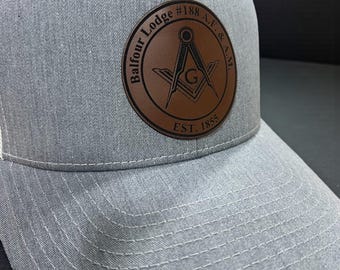 May include: Gray baseball cap with a brown leather patch. The patch features the words "Balfour Lodge #188 A.F. & A.M." and "EST. 1855" surrounding a compass and square symbol. The cap has a curved brim and white stitching.