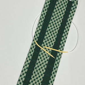 May include: Green and white checkered fabric knitting needle case with a handle. The case has two dark green stripes down the center. Two wooden knitting needles and a circular needle are inside the case.