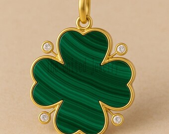 May include: A gold-colored pendant in the shape of a four-leaf clover. The clover is made of green malachite with gold trim and small, round, clear gemstones at each leaf intersection. The pendant has a loop at the top for a chain.