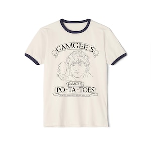 Peut inclure: T-shirt crème à col et manches bleu marine, orné d'une illustration en noir et blanc. Le motif affiche "GAMGEE'S FAMOUS PO-TA-TOES" avec une personne tenant une pomme de terre. Le texte en bas dit "BOILED, MASHED, STUCK IN A STEW."