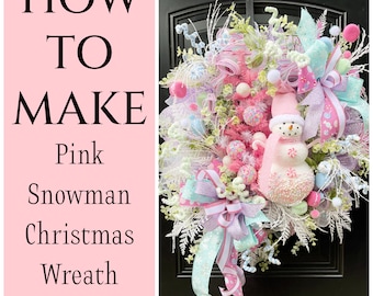 May include: How to Make a Pink Snowman Christmas Wreath. A pink snowman with a white scarf and a pink hat is the centerpiece of this festive wreath. The wreath is decorated with pink, white, and blue ribbons, bows, and other embellishments.
