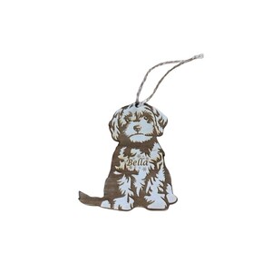 May include: A wooden Christmas bauble shaped like a dog with the name "Bella" engraved on it. The bauble is brown and white and has a string for hanging.