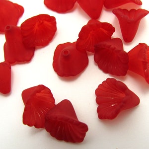 May include: A group of red plastic flower-shaped beads. The beads have a scalloped edge and a pointed base.