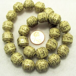 May include: A strand of off-white beads with gold lettering. The beads are cube shaped and have a smooth, polished finish.