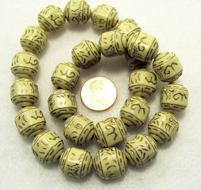 May include: A strand of off-white beads with gold lettering. The beads are cube shaped and have a smooth, polished finish.