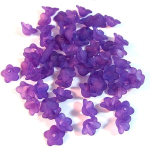 May include: A large group of purple flower-shaped beads. The beads are made of plastic and have a translucent finish.