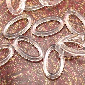 May include: A group of clear plastic oval rings, scattered on a red and gold background.