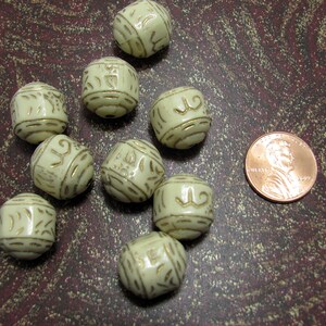 May include: Nine off-white ceramic beads with gold accents. Each bead has a different design. The beads are approximately the size of a US penny.