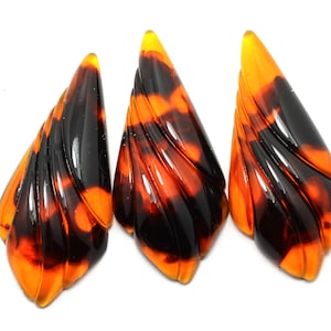 May include: Three brown and orange tortoise shell earrings with a swirl design.