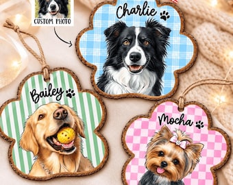 May include: Three paw-shaped wooden ornaments with jute twine hangers. Each features a custom dog portrait, a name, and a paw print icon. The top ornament has a blue plaid background and the name Charlie. The others feature Bailey and Mocha.
