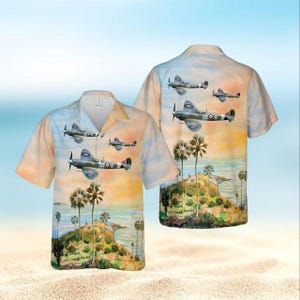 May include: Short-sleeved button-down shirt featuring a tropical scene with palm trees, a beach, and several vintage fighter planes. The shirt has a light blue, orange, and yellow gradient background. The planes have a green and gray color scheme.