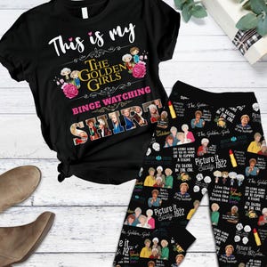 Può includere: Set di maglietta e leggings neri a tema "Golden Girls". La maglietta recita "This is my Golden Girls Binge Watching Shirt". I leggings presentano un motivo ripetuto di personaggi e citazioni.