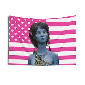 May include: A rectangular tapestry with a pink and white American flag design. The image features a blue-skinned humanoid figure with dark hair and yellow eyes. The figure is wearing jewelry. The tapestry is likely made of fabric.