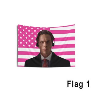 Könnte beinhalten: Ein Wandteppich mit einer rosa und weißen amerikanischen Flagge, die einen Mann im Anzug und mit Kopfhörern zeigt. Die Flagge hat einen rosa Hintergrund mit weißen Streifen und weißen Sternen. Der Text "Flag 1" befindet sich unten.