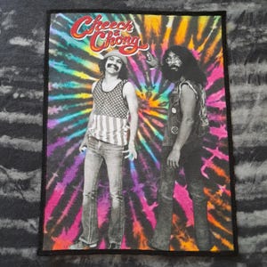 May include: Rectangular patch featuring the duo Cheech & Chong against a vibrant tie-dye background. The patch showcases the comedy duo in a black and white image, with the Cheech & Chong logo in red and yellow at the top. The background is a swirl of pink, purple, blue, and yellow.