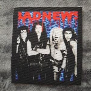 May include: A black square patch featuring the band Bad News. The band members are depicted in a stylized illustration with the band's name in dripping red letters against a blue leopard print background.