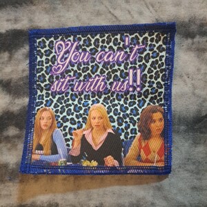 May include: Square patch with a blue border featuring a leopard print background and the text "You can't sit with us!!". The patch depicts three women at a table.
