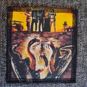 May include: A square fabric patch with a black stitched border featuring a printed graphic. The top section shows silhouettes of four figures against a bright yellow sunset sky. The bottom section displays a stylized, abstract flame-like design.
