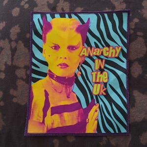 May include: A rectangular patch featuring a stylized portrait with yellow and purple tones, set against a blue and black zebra stripe background. The text "ANARCHY IN THE UK" is prominently displayed.