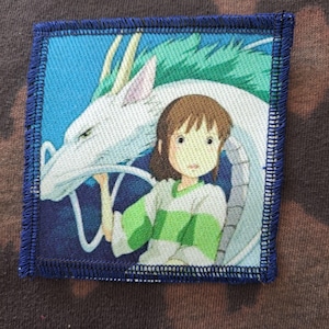 May include: Square patch featuring an anime-style illustration of a girl and a white dragon. The patch has a blue border with stitched edges. The girl wears a green and white striped shirt. The dragon has green and white details.