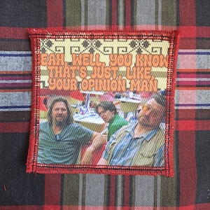 May include: Square patch with a red border featuring a scene with three men and the text "Yeah, well, you know that's just like your opinion man." The patch has a woven design and is set against a plaid background.